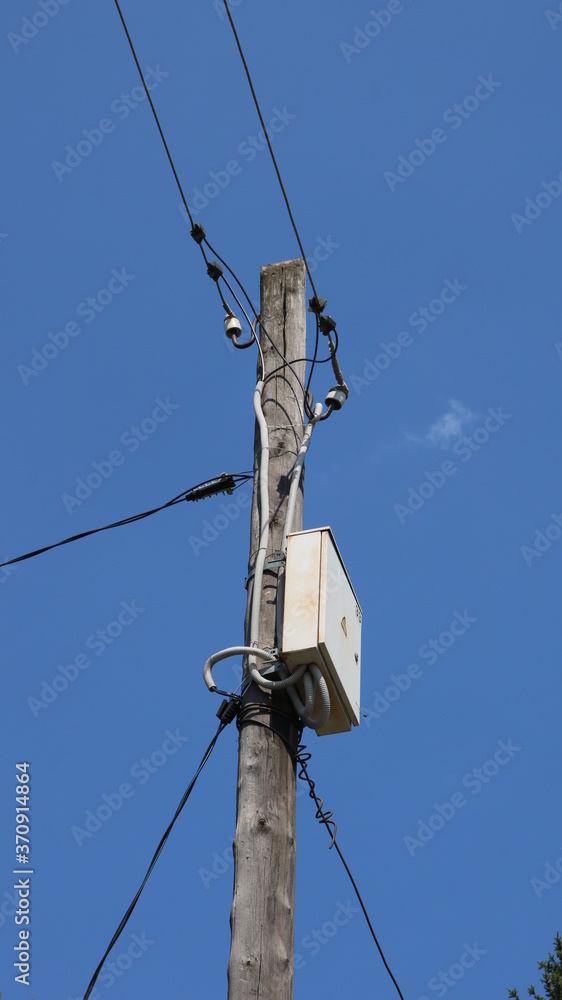 junction box with a counter with electric wires running in different directions on a wooden post against a blue sky background junction box with a counter with electric wires running in different directions on a wooden post against a blue sky background