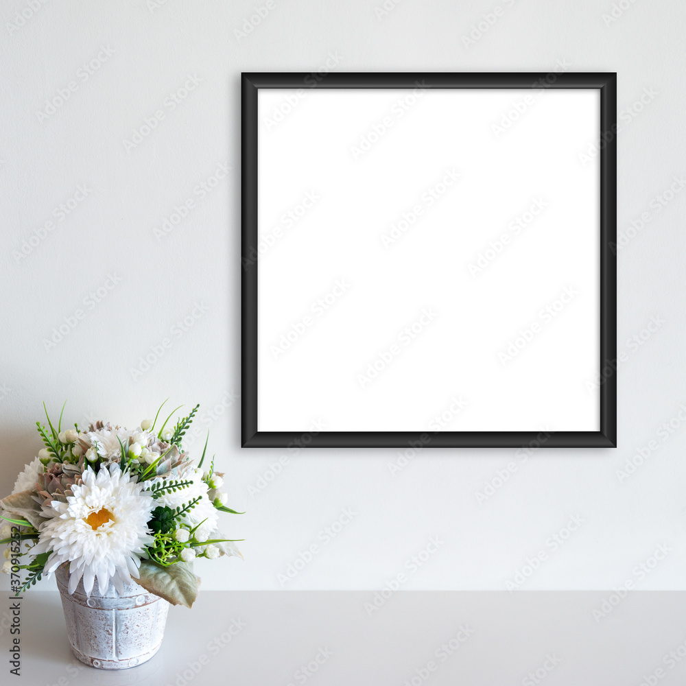 Black frame mockup on white wall with pot of flowers on white surface. Copy space. Black frame mockup on white wall with pot of flowers on white surface. Copy space.