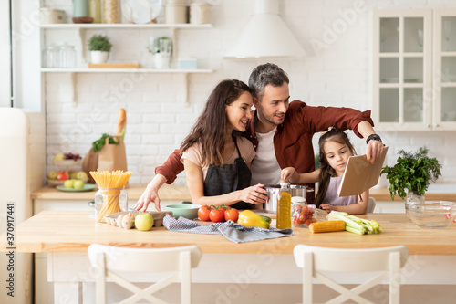 Fotografie Happy family cooking together at home kitchen