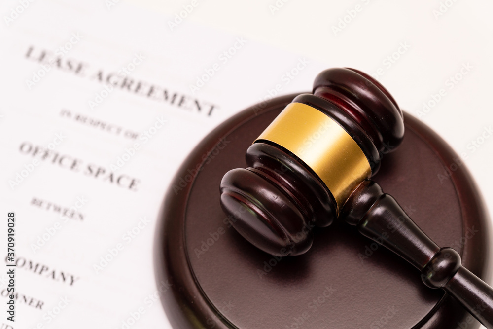 Concept of lease law or tenancy law: wooden gavel is placed on the cover of lease agreement. The company name is supposed name.