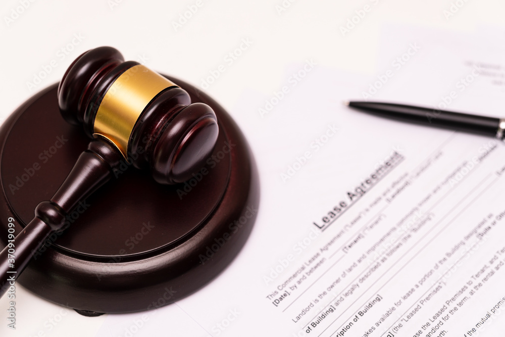 Concept of lease law or tenancy law: the first page of lease agreement was is placed near the wooden gavel.