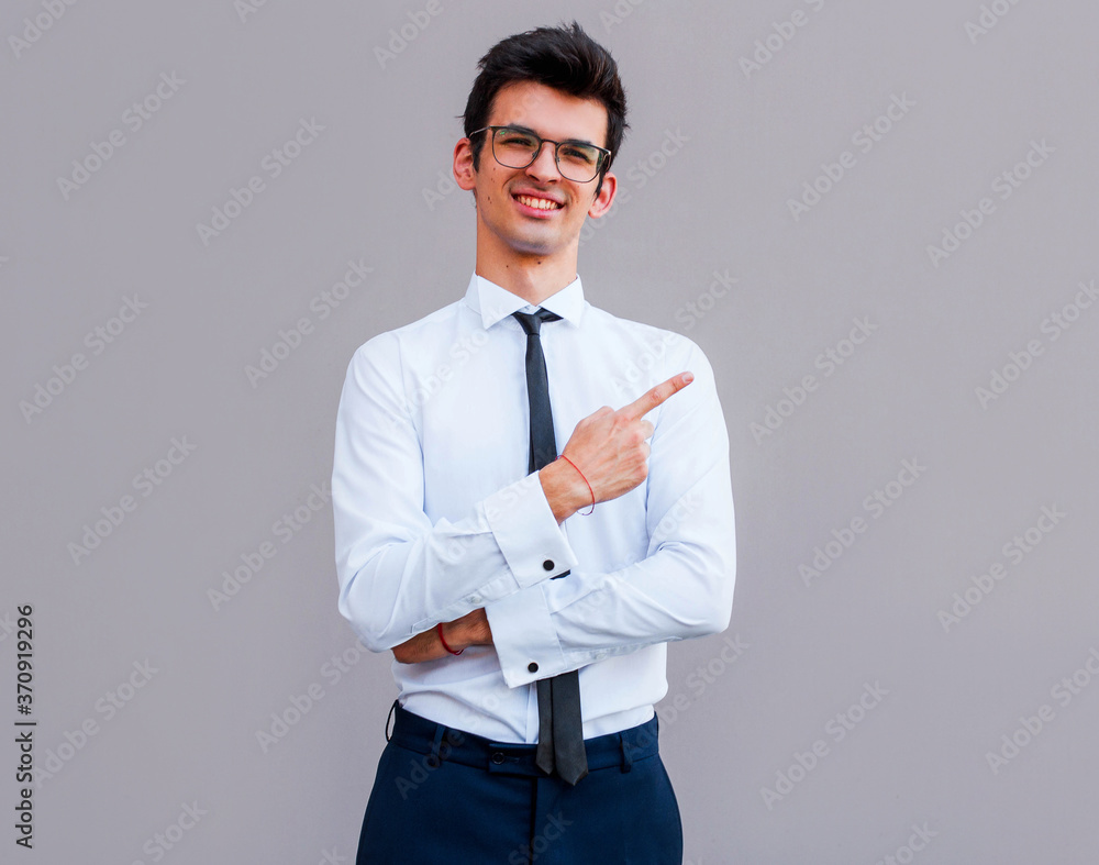 Young handsome businessman with beaming smile pointing with finger Young handsome businessman with beaming smile pointing with finger