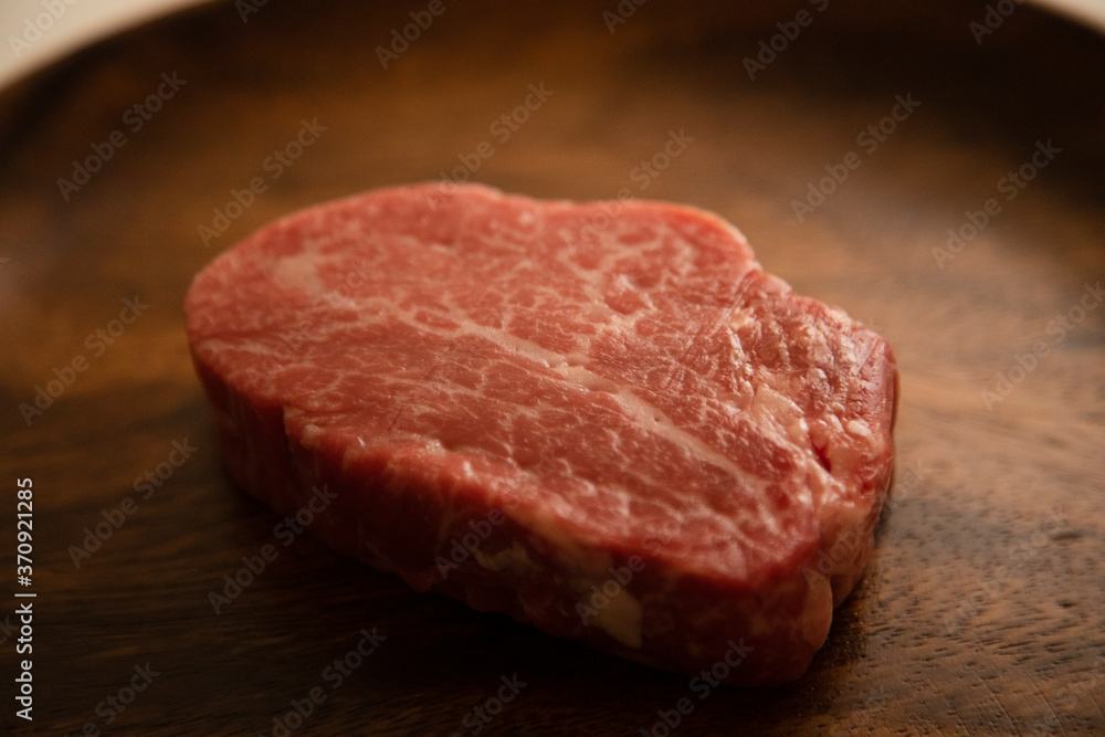 Raw Fillet Mignon Steak on the wooden round plate Raw Fillet Mignon Steak on the wooden round plate