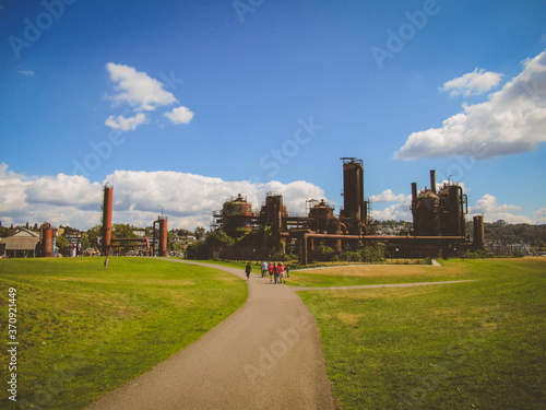 Old industrial buildings and people walking in Gas Works Park in Seattle on a sunny summer day.