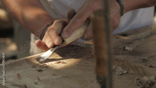 woodcarver processes a walnut wood board with a chisel. artisan makes a tea tray