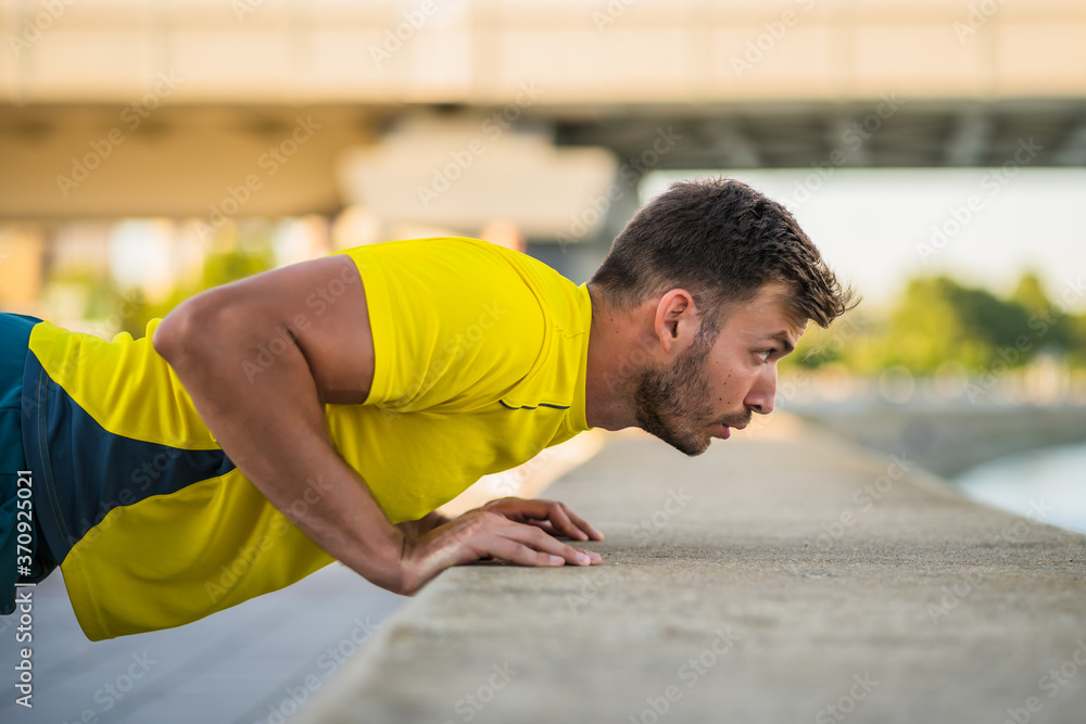 Young man is exercising outdoor. He is doing push-ups. Young man is exercising outdoor. He is doing push-ups.