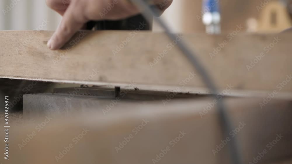 A wood craftsman is cutting an old walnut plank with a hand-held electric fraser. A wood craftsman is cutting an old walnut plank with a hand-held electric fraser.