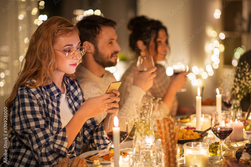 holidays and people concept - woman with smartphone at dinner party with friends at home holidays and people concept - woman with smartphone at dinner party with friends at home