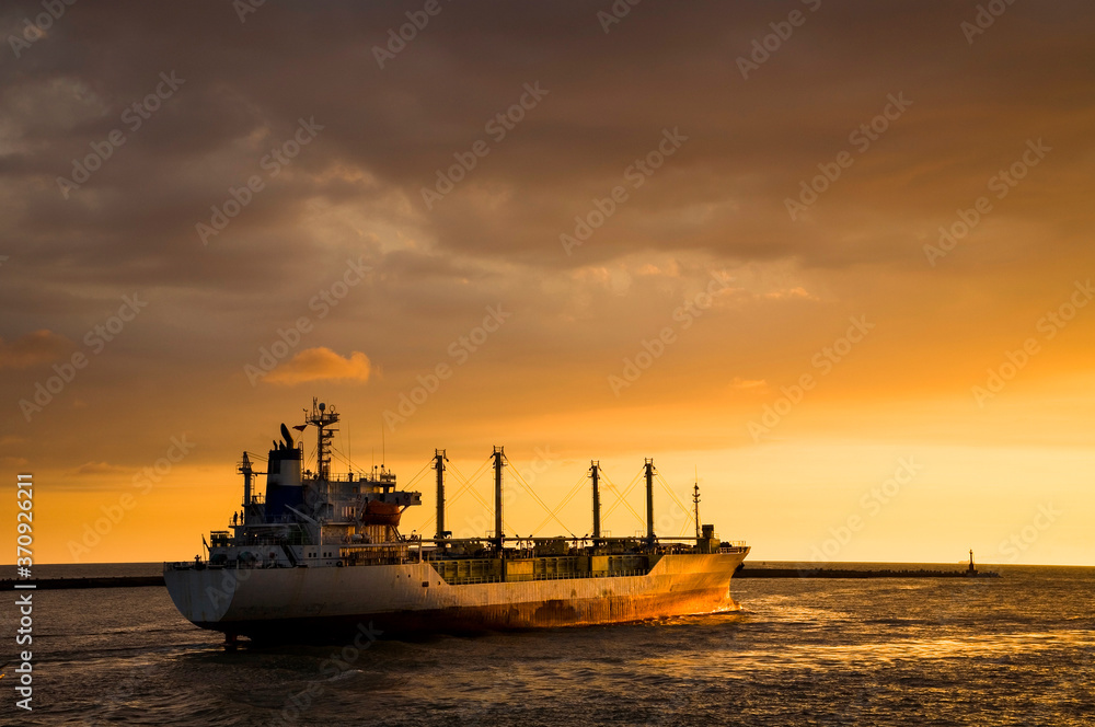 Sunset into the sea with the large ship silhouette.