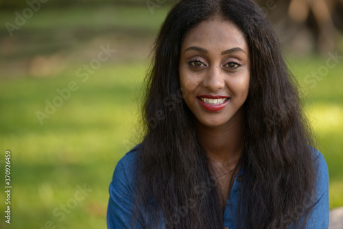 Happy young beautiful African woman at the park outdoors