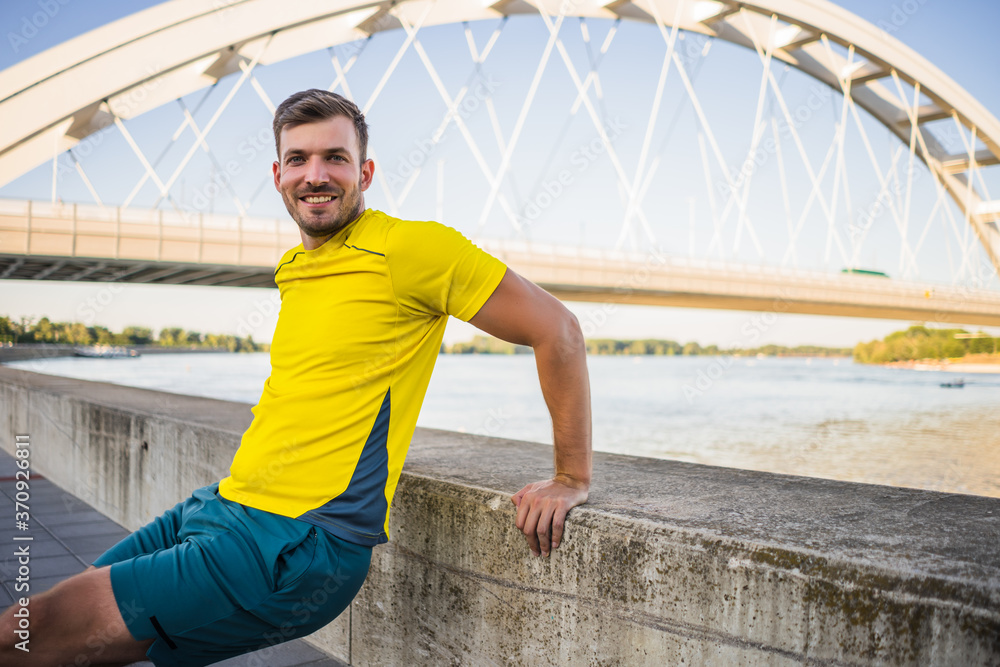 Young man is exercising outdoor. He is doing reverse push-ups.