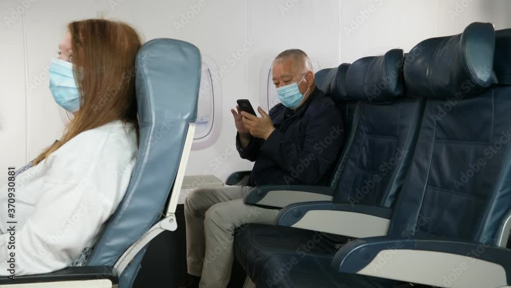 4K: Male Asian Airplane Passenger using a Phone and wearing Face mask on plane journey. Air Travel. Tracking Shot. Stock Video Clip Footage 4K: Male Asian Airplane Passenger using a Phone and wearing Face mask on plane journey. Air Travel. Tracking Shot. Stock Video Clip Footage