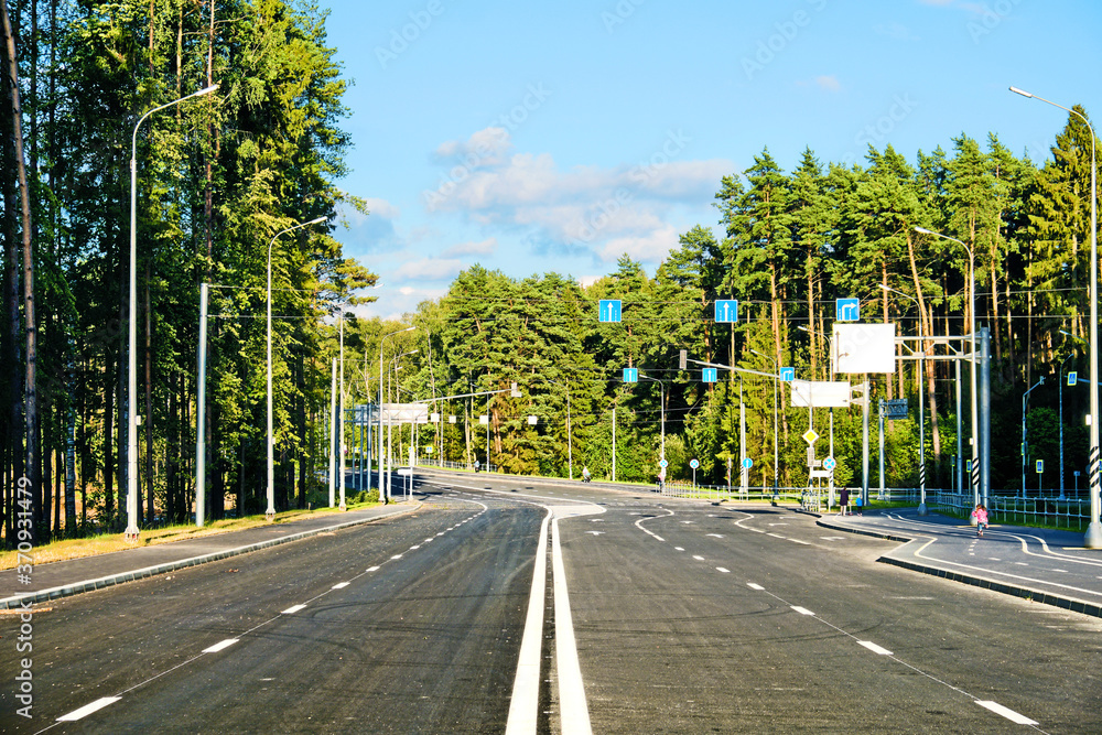 modern street in moscow city russia with pedestrian sidewalk and bike lane against forest background. Wide view of city transportation infrastructure. Empty road. Asphalt freeway. Urban landscape
