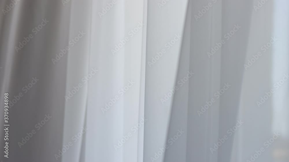 Waving white tulle near the window Waving white tulle near the window