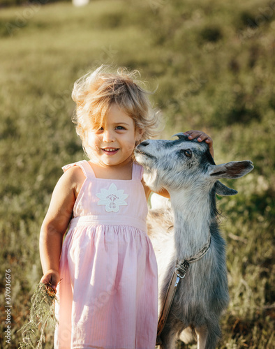 girl with baby goat on farm outdoors. Love and care. Village animals. happy child hugs goat, concept of unity of nature and man. Friendship of child and animals. Happy childhood. Goat kissing girl