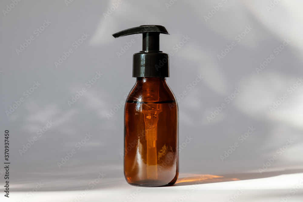 Brown amber glass bottle with lotion pump dispenser. Cosmetic container for shampoo, essential oil, lotion soap Brown amber glass bottle with lotion pump dispenser. Cosmetic container for shampoo, essential oil, lotion soap