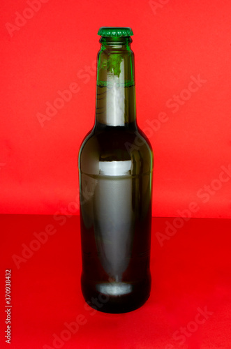 Vertical image.One bottle of beer on the bright and light red background