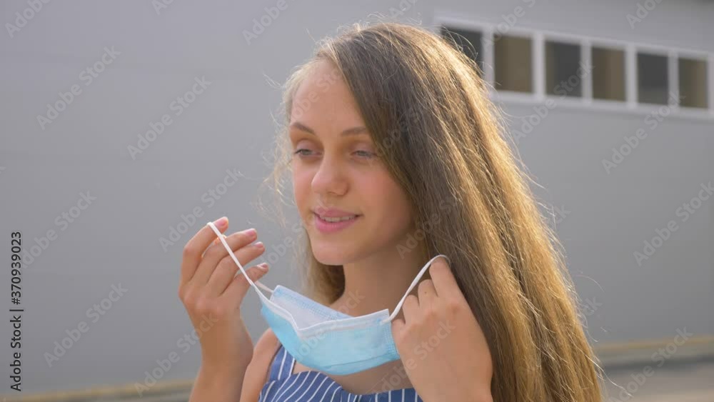 A young girl removes a medical mask. The girl takes a deep breath of fresh air. Corona virus vaccine. A teenage student stands in a College Park without a mask. A young girl removes a medical mask. The girl takes a deep breath of fresh air. Corona virus vaccine. A teenage student stands in a College Park without a mask.