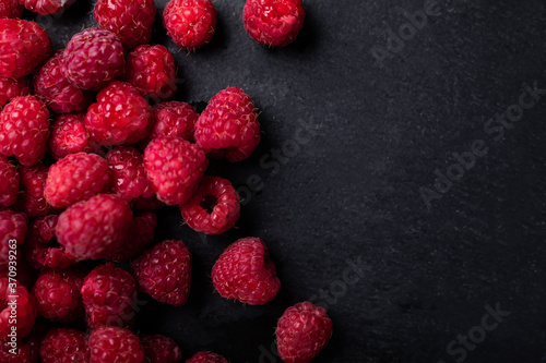Raspberries on a black stony background, top view with a copy-space.
