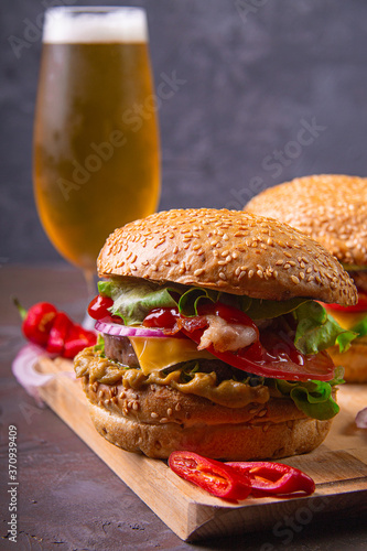 Hamburger stacked with beef patty, bacon, cheddar cheese, red onions, tomato, lettuce, mustard and ketchup. Served with a beer and chili pepper and onion rings.