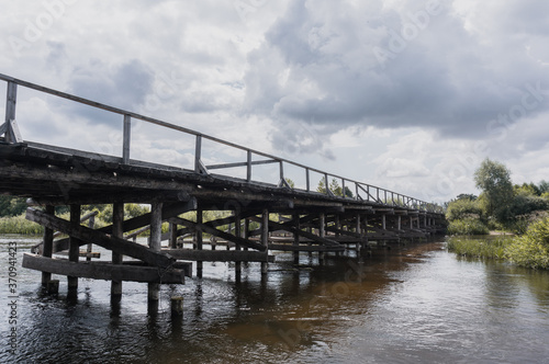 Old wooden bridge over the river in cloudy weather,