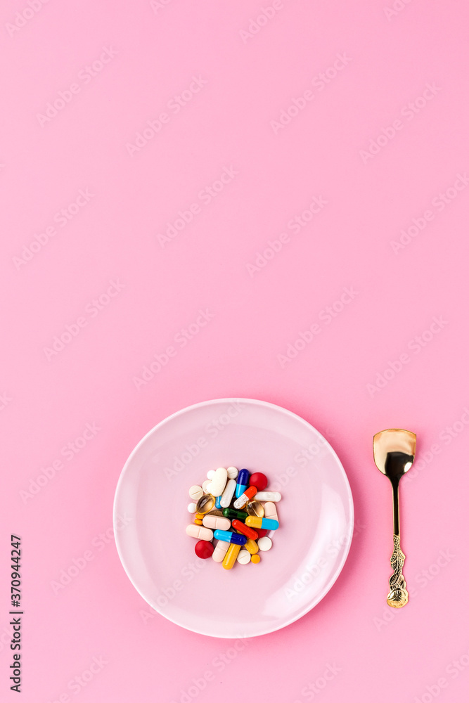 Vibrant pills on the plate with pink background
