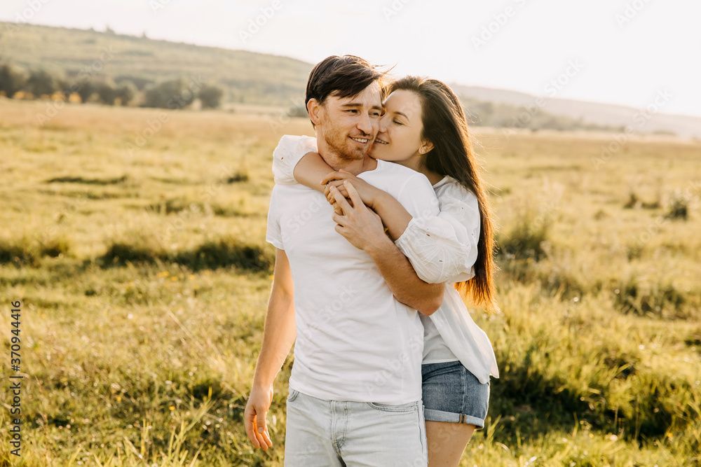 Young couple hugging and smiling outdoors in an open field on summer day. Young couple hugging and smiling outdoors in an open field on summer day.