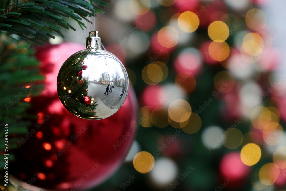 Red and silver christmas balls on a fir branches on festive golden lights background, street illumination. New Year tree with decorations, magic of a holiday for background Red and silver christmas balls on a fir branches on festive golden lights background, street illumination. New Year tree with decorations, magic of a holiday for background