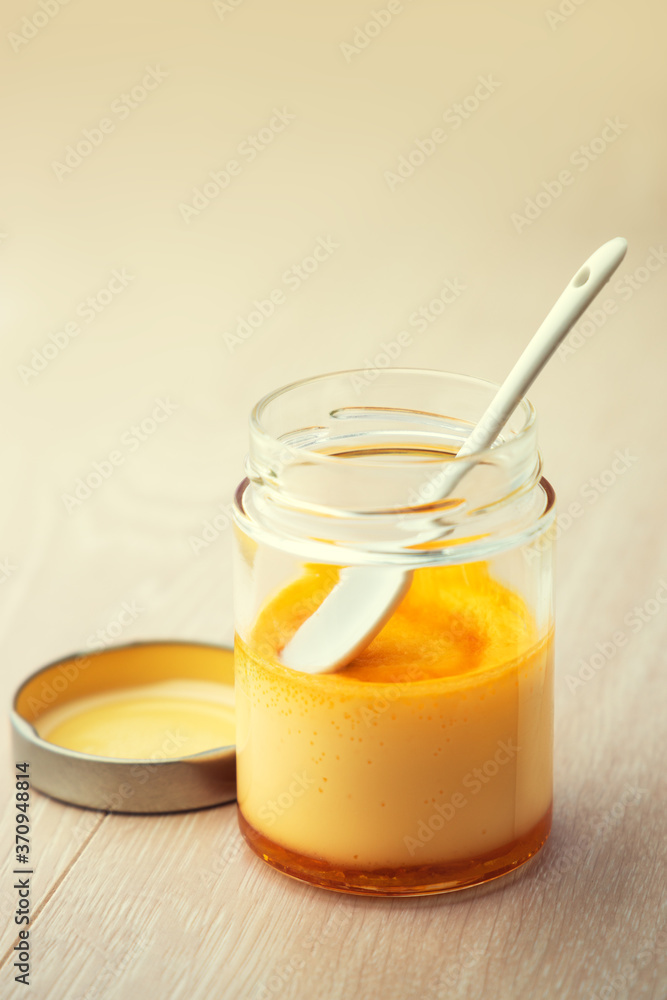 Cream caramel in a jar isolated on wooden background Cream caramel in a jar isolated on wooden background