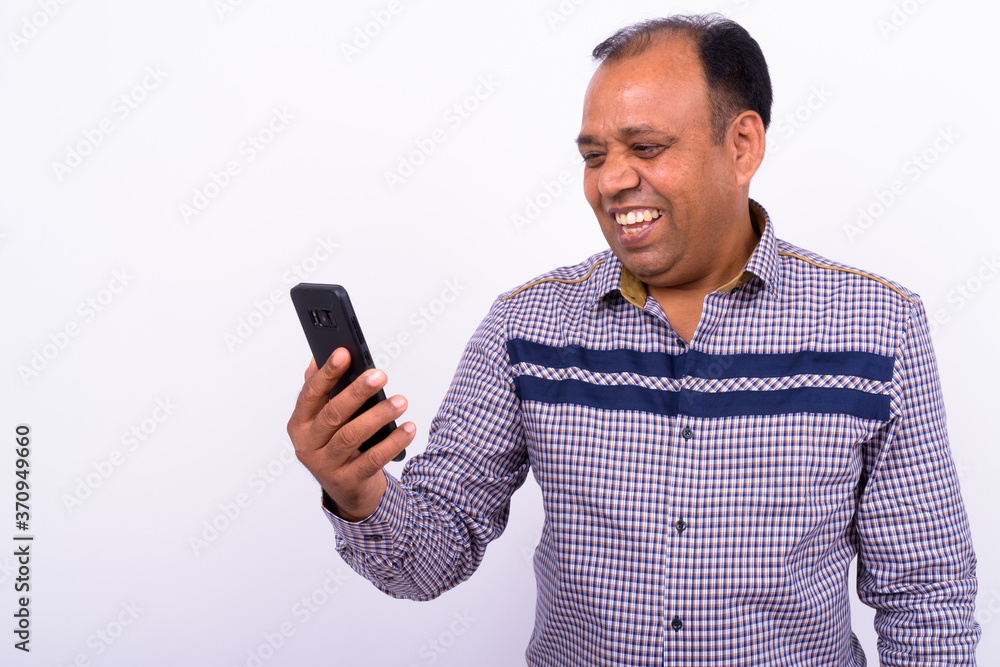 Portrait of happy mature overweight Indian businessman using phone Portrait of happy mature overweight Indian businessman using phone
