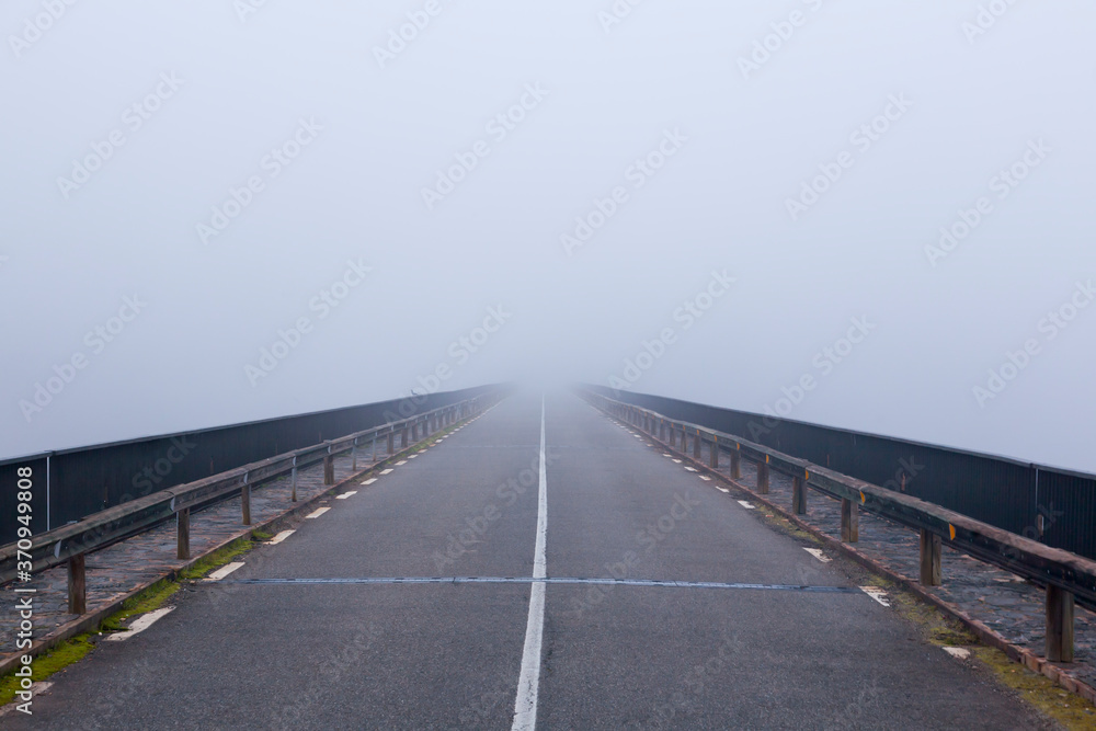 Empty foggy rural asphalt highway perspective with white line