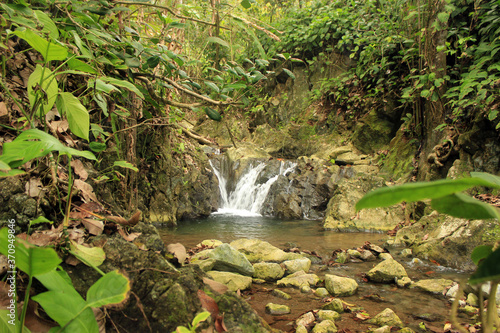 Waterfall in the middle of the jungle with natural pool and tropical trees in Costa Rica