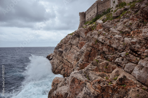 Obraz na płótnie wave crashing against the rocks with Dubrovnik's walls in the background w salonie