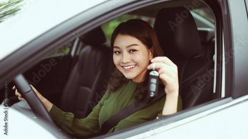 Beautiful young girl driver with car key in hand, happy owner of a new automobile © makistock