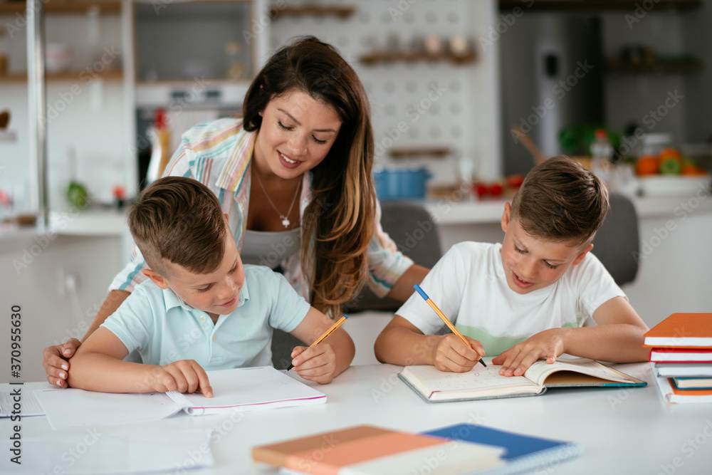 Mother helping her sons with homework at home. Little boys learning at home.. Mother helping her sons with homework at home. Little boys learning at home..