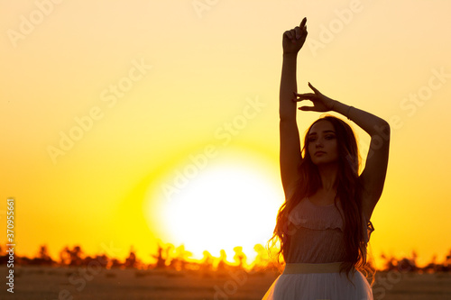 graceful silhouette figure of young woman walking in field at sunset  beautiful romantic girl with long hair outdoors