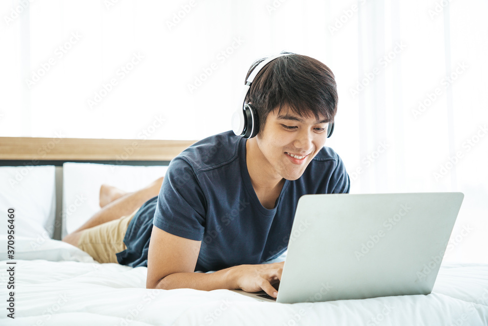 Happy man using Laptop computer and checking good News in the Bedroom. COPY SPACE. Trading. Watching Movie. WORK FROM HOME Concept. Happy man using Laptop computer and checking good News in the Bedroom. COPY SPACE. Trading. Watching Movie. WORK FROM HOME Concept.