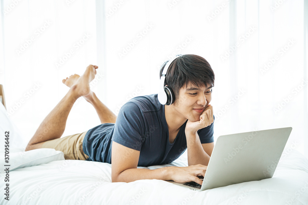 Happy man using Laptop computer and checking good News in the Bedroom. COPY SPACE. Trading. Watching Movie. WORK FROM HOME Concept. Happy man using Laptop computer and checking good News in the Bedroom. COPY SPACE. Trading. Watching Movie. WORK FROM HOME Concept.