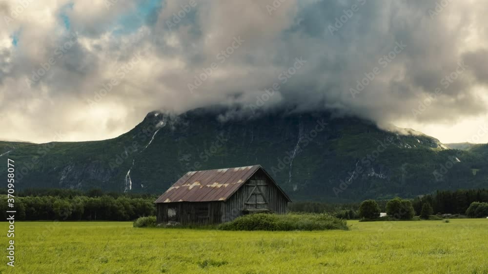 Wooden Barn House Surrounded By Lush Green Grass With Mountain At The Background - Wide Shot Wooden Barn House Surrounded By Lush Green Grass With Mountain At The Background - Wide Shot