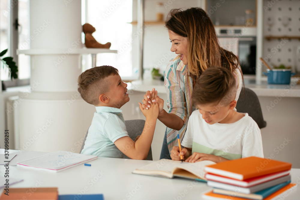 Mother helping her sons with homework at home. Little boys learning at home.. Mother helping her sons with homework at home. Little boys learning at home..