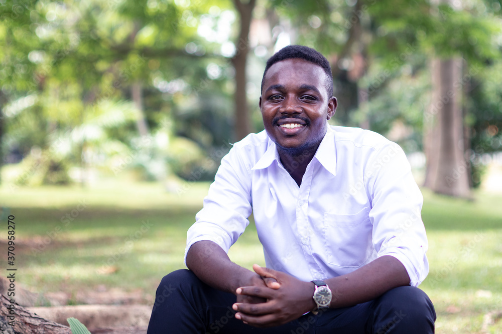 Fototapeta premium African business man sitting and smiling with green nature backgroung