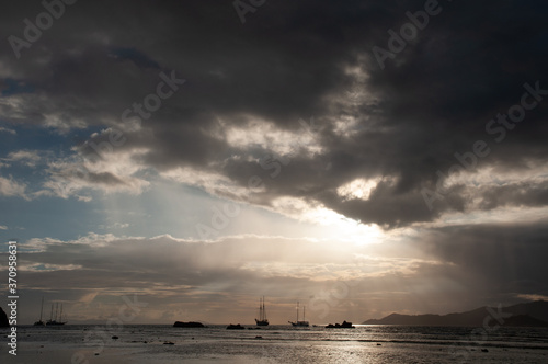 Dramatic sky with clouds and sunbeam over the Indian Ocean with sailing boat during sunset.