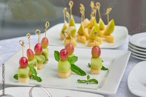 canapes with grapes and cheese are on a white plate. close up.