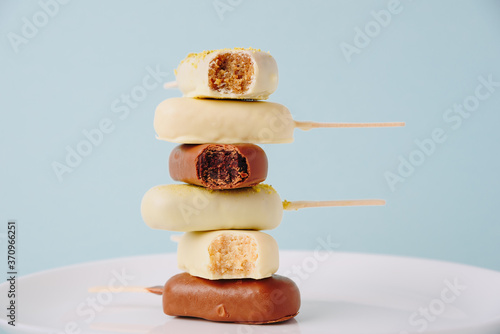Chocolate cake in the form of ice cream on a stick on a white plate and a colored background