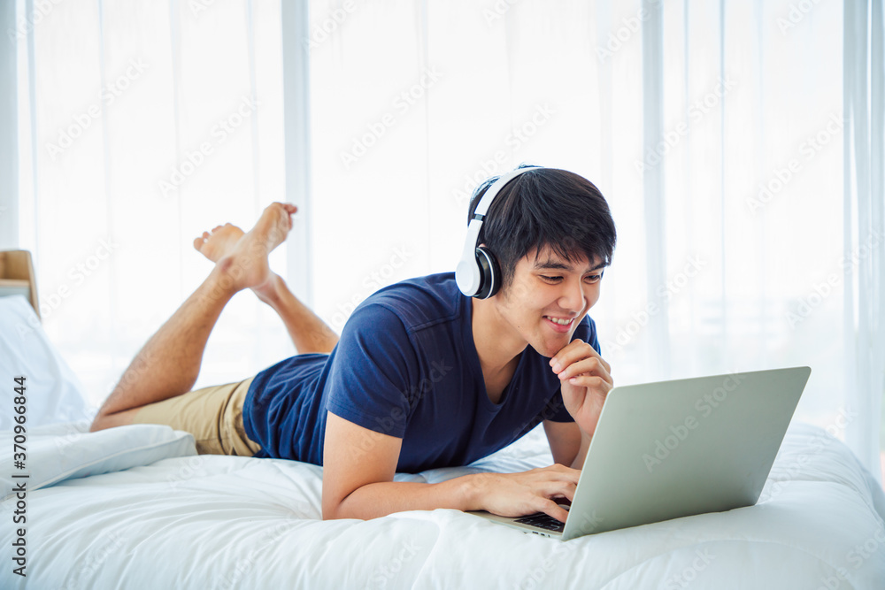 Happy man using Laptop computer and checking good News in the Bedroom. COPY SPACE. Trading. Watching Movie. WORK FROM HOME Concept. Happy man using Laptop computer and checking good News in the Bedroom. COPY SPACE. Trading. Watching Movie. WORK FROM HOME Concept.