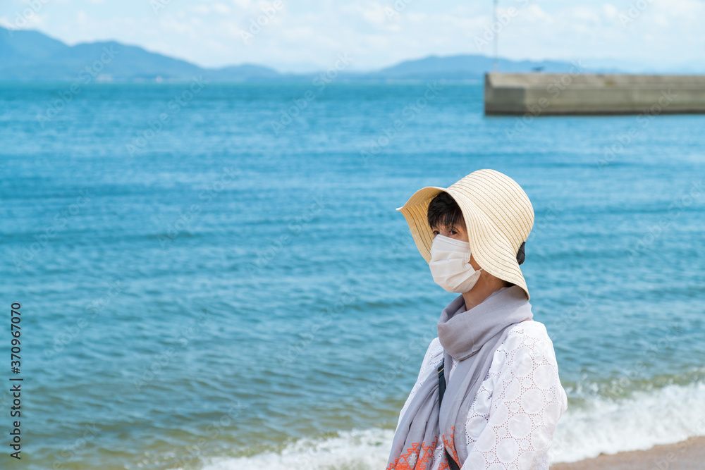 海岸を旅行中のマスクをした中年女性