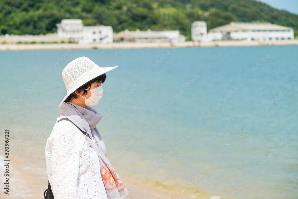 海岸を旅行中のマスクをした中年女性