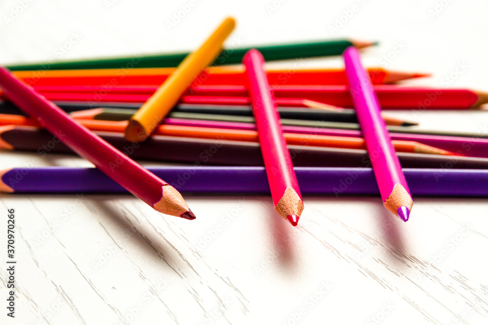 Obraz premium many colored sharpened pencils lie on a white wooden table