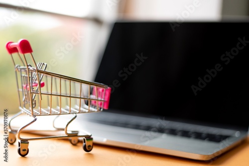 Close-Up Of Laptop And Shopping Cart By Credit Card On Table