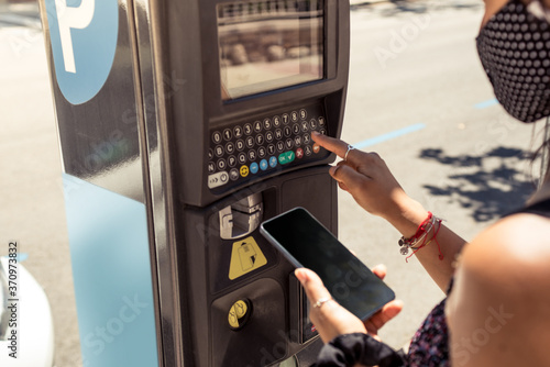Close up photography of woman using parking meter machine with the smartphone. photo